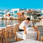 Οι ειδικότητες της πρώτης γραμμής, όπως οι ρεσεψιονίστ, οι μάγειρες και το προσωπικό καθαριότητας, καταγράφουν τη μεγαλύτερη αύξηση αποδοχών στον ελληνικό τουρισμό το 2026, καθώς οι εργοδότες αναγκάζονται να προσφέρουν μισθούς σημαντικά υψηλότερους από τα όρια των συλλογικών συμβάσεων για να καλύψουν τα χιλιάδες κενά.